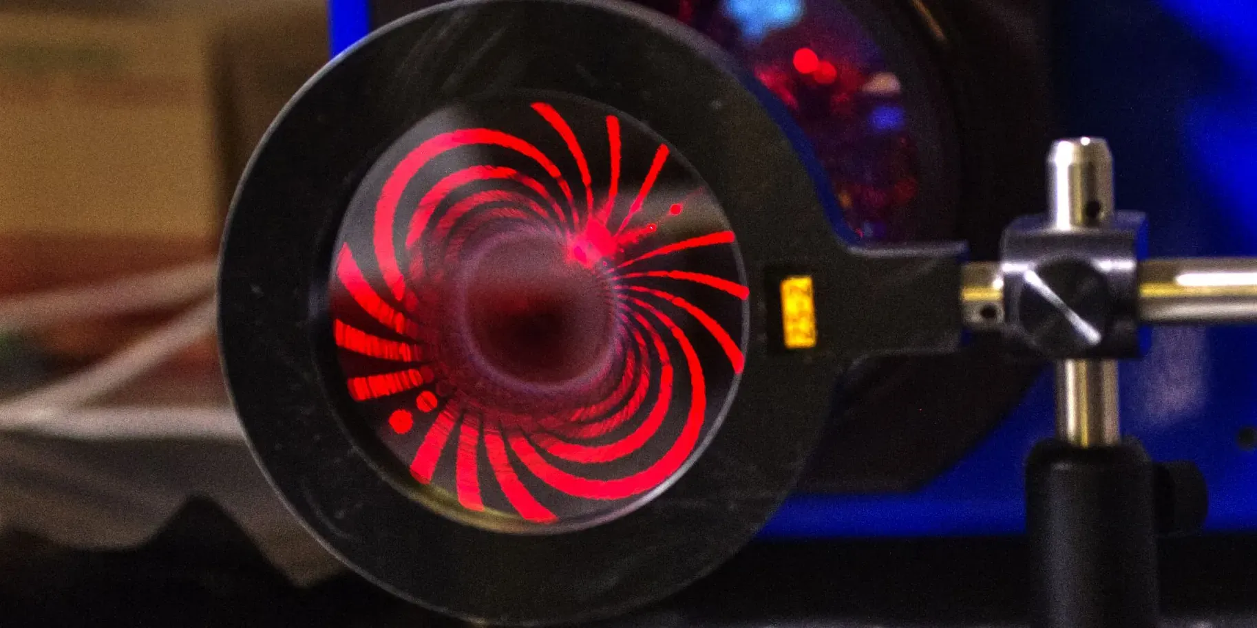 A photon-sieve optic illuminated with red laser light during a NASA optical test.